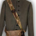 nr5 Ubiór powstańczy oficera strzelców 1863 r. – czapka z siwego sztucznego baranka z karmazynową kokardą, na której widoczny jest metalowy Orzeł, świtka sukienna szara, pas oficerski z taśmy złotej z haftowanymi orłami, torba myśliwska skórzana, pod klapą gniazda na naboje, z boku kieszeń na manierkę, pas do torby pokryty zieloną taśmą