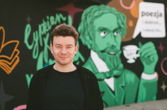 Krzysztof Szczepaniak na tle muralu NCK 